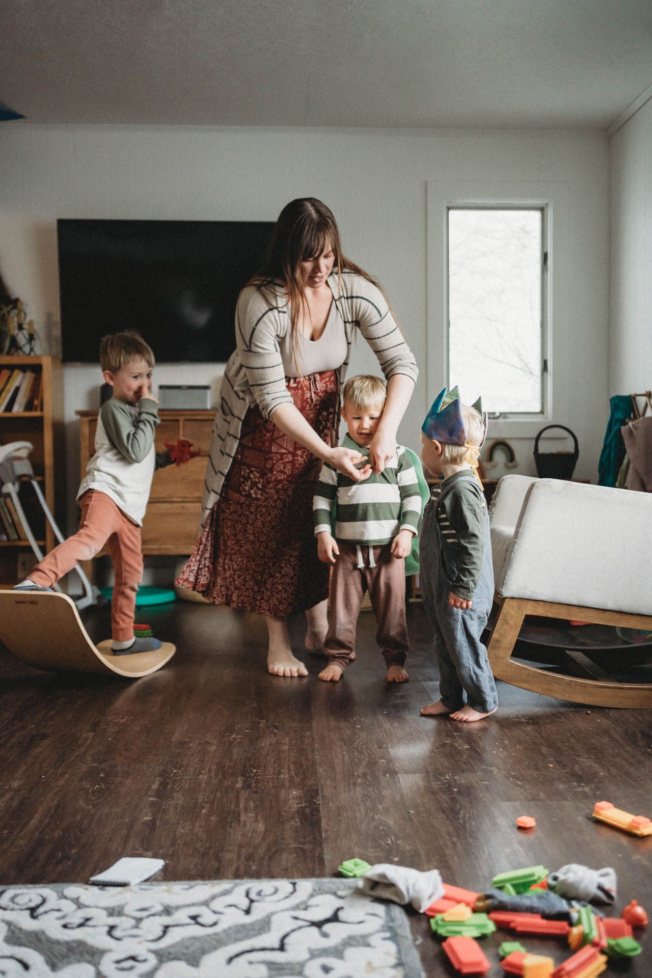 Indoor playtime with wooden balance boards and scattered toys on hardwood floor.