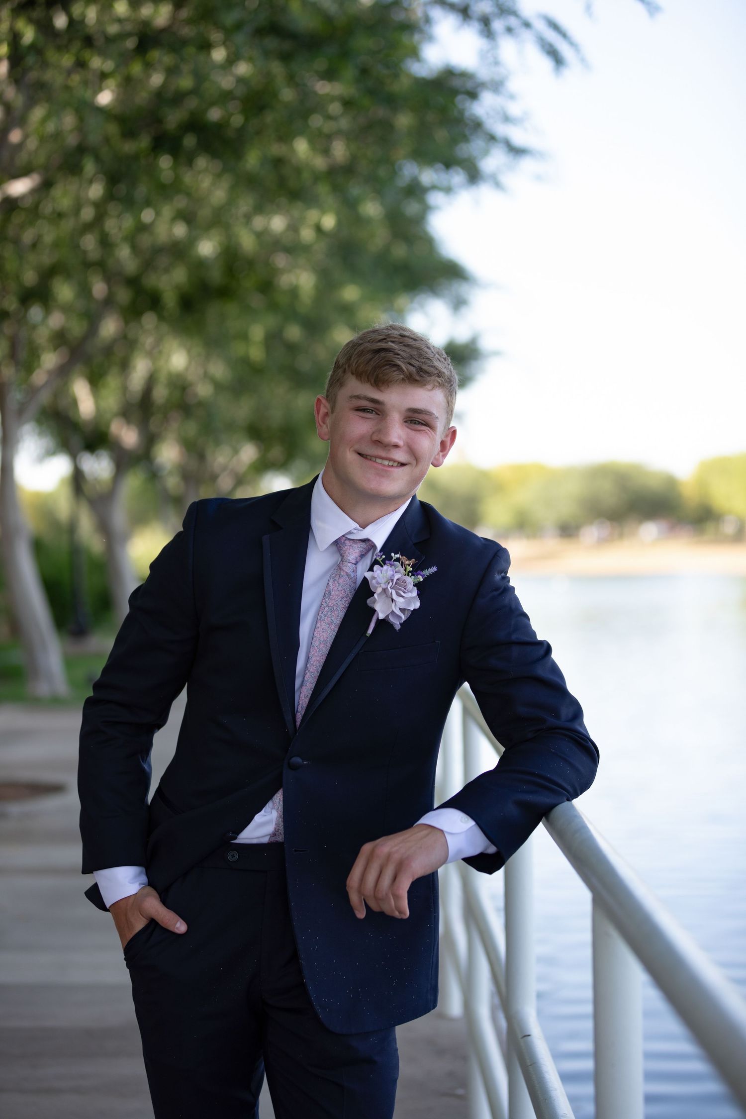 High school senior at prom, dressed up and smiling at the camera.