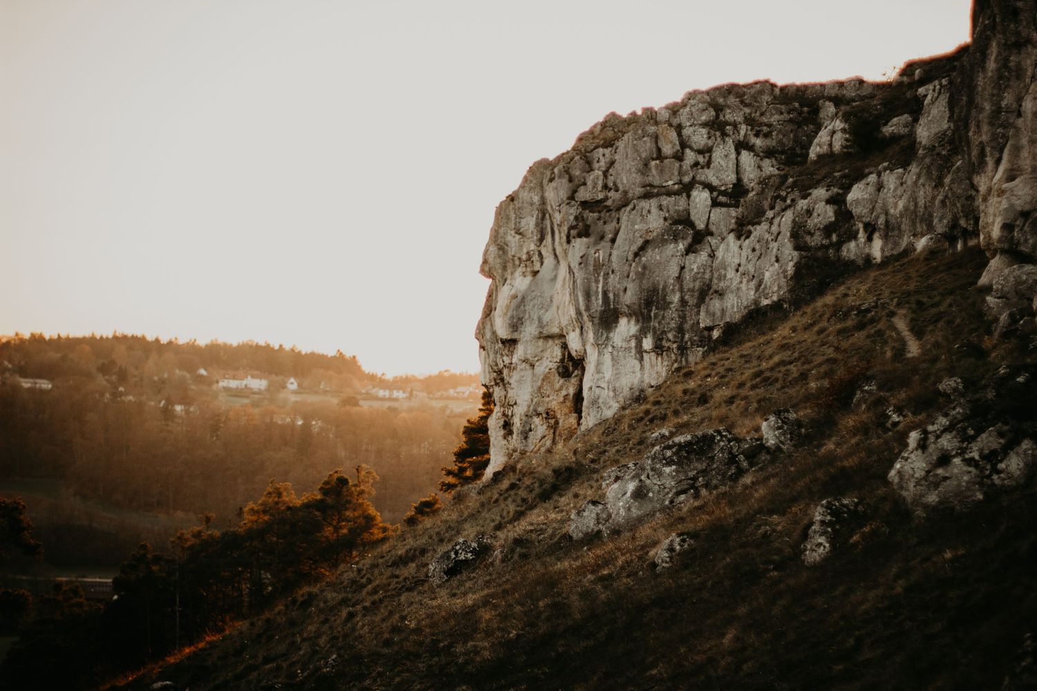Dramatic mountain landscape at sunset with rocky cliffs and warm lighting.