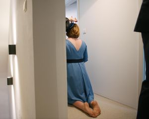 Person in blue dress seen from behind in a white hallway.