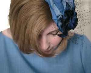 Close-up view of a blue floral fascinator against blonde hair.