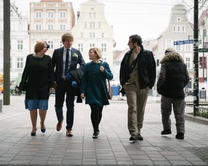 A group of people walking together and laughing on a city street with historic buildings in the background.