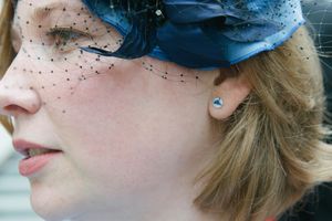 Close-up profile view of a blue feathered fascinator and crystal earring.