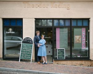 A couple standing outside The Color Meeting shop with chalkboard signs on display.