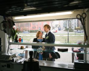 A couple seen through a window frame sharing a drink together.