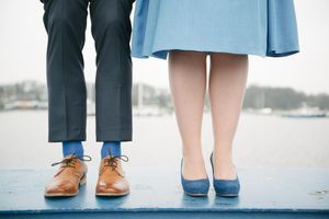 Close-up view of formal shoes and hemlines on a blue painted surface.