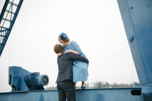 A romantic moment captured between a couple on industrial maritime equipment.