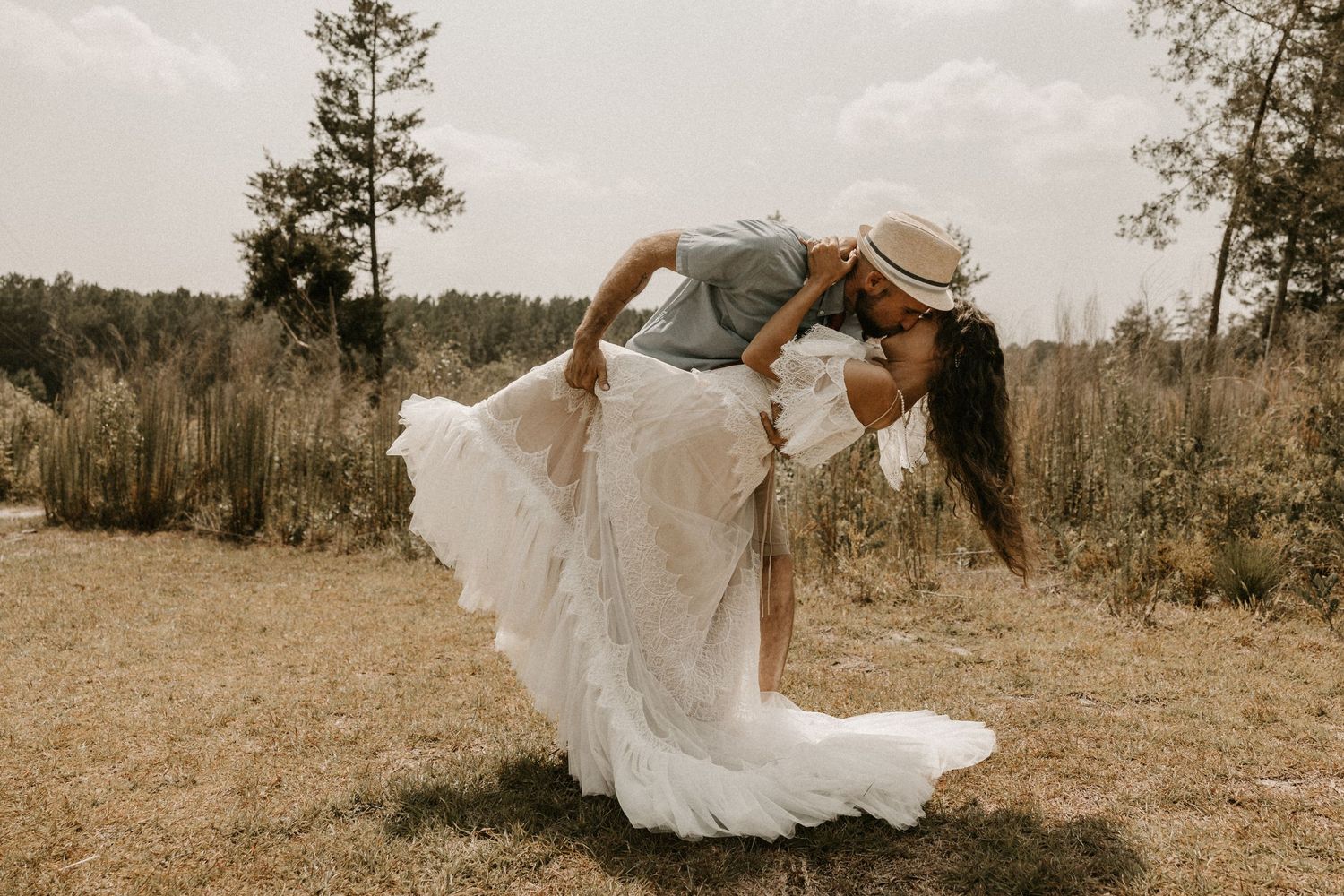 Dramatic wedding pose with flowing white dress in outdoor setting.