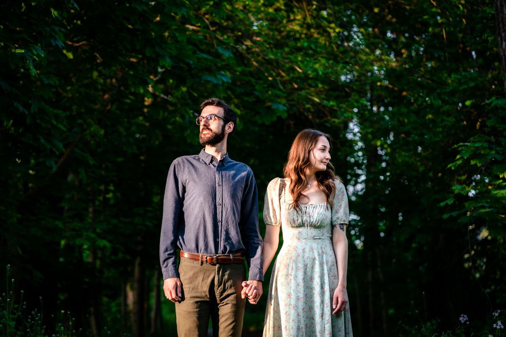 Playful couple embraces while standing on a wooded nature trail.
