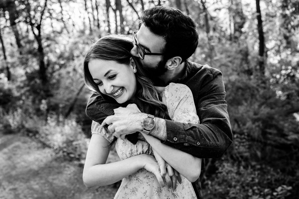A romantic black and white portrait of a couple embracing outdoors.