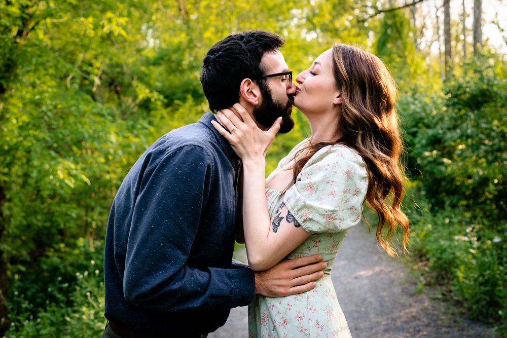A tender moment shared between a couple on a forest path.