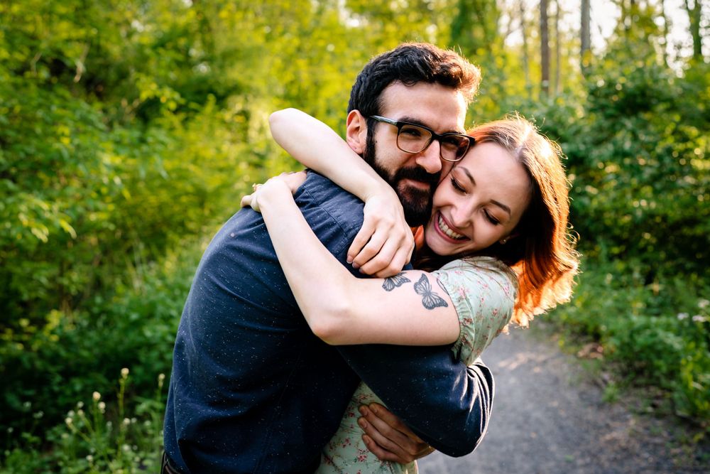 A joyful embrace captured in a sunny forest setting.