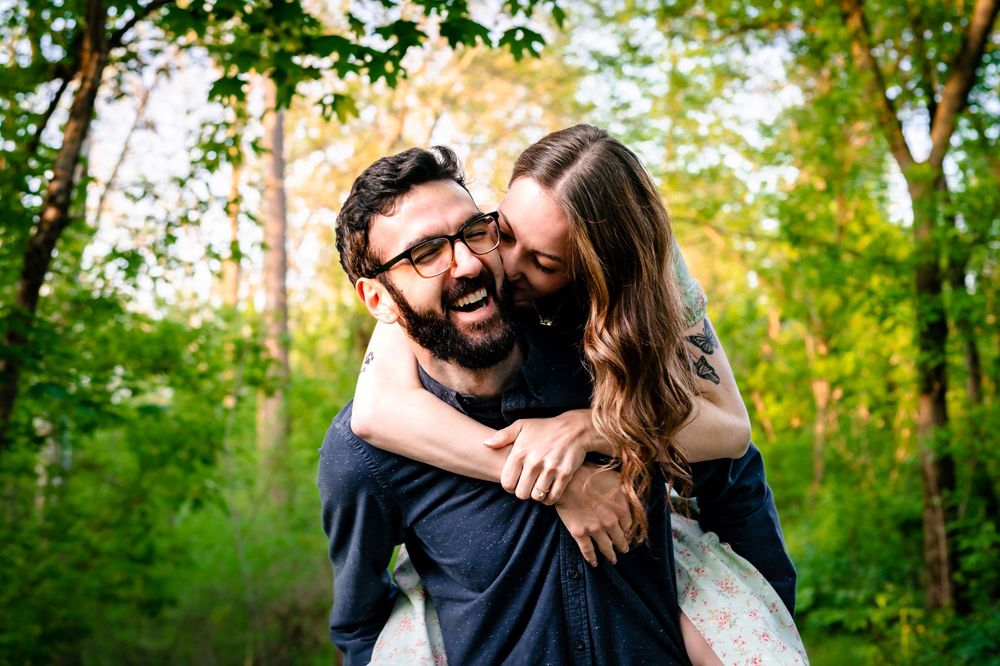 Natural light engagement photos showing tender moments between a couple in a wooded setting.