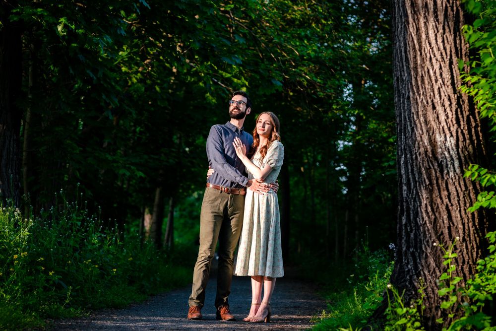 Couple walking together on a tree-lined path in a serene woodland setting.