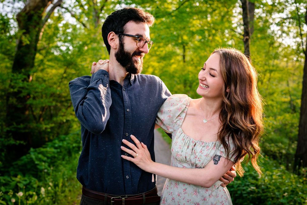 A romantic couple shares intimate moments in a lush green forest setting during golden hour.