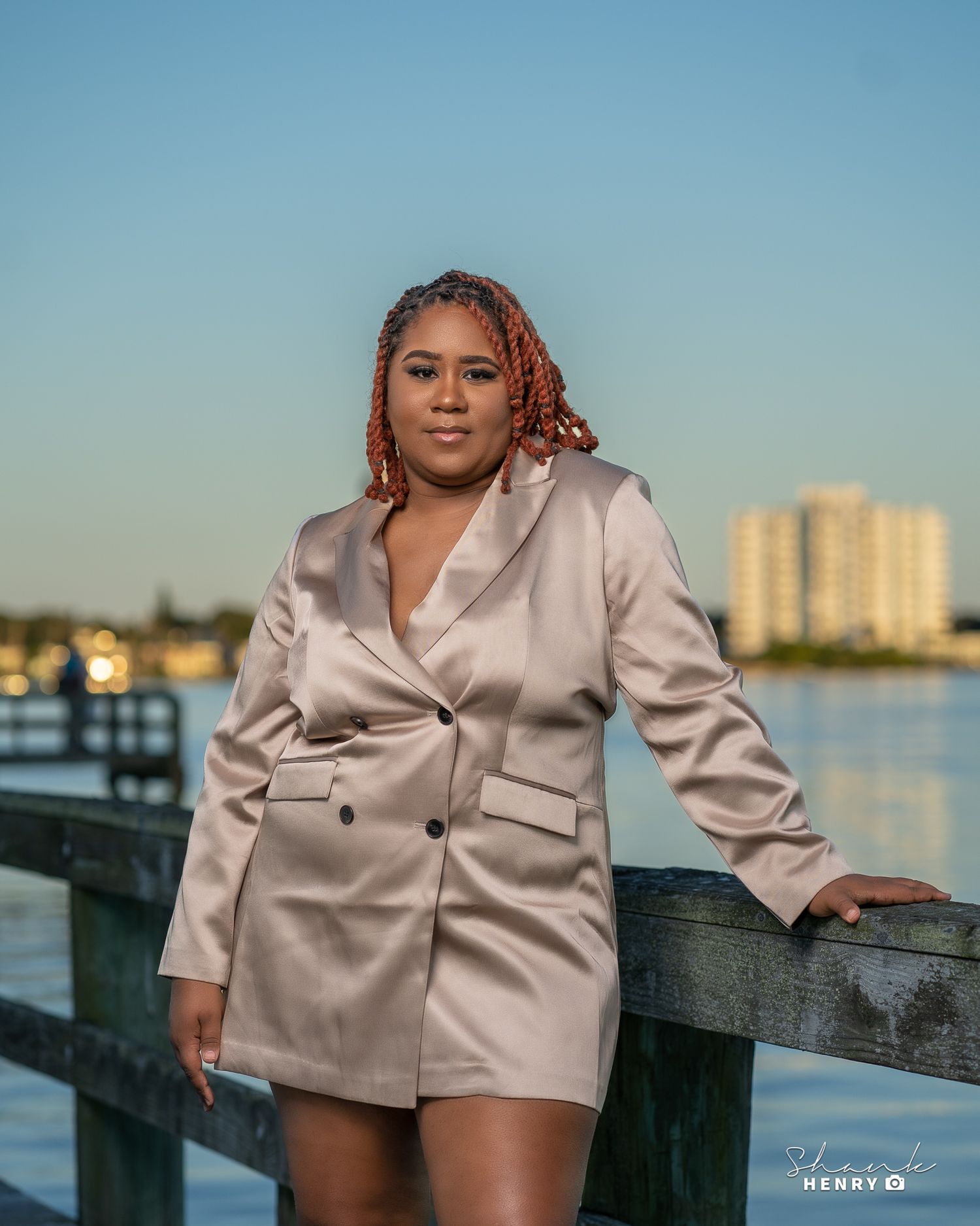Stylish pose in champagne colored blazer dress on waterfront pier at sunset.