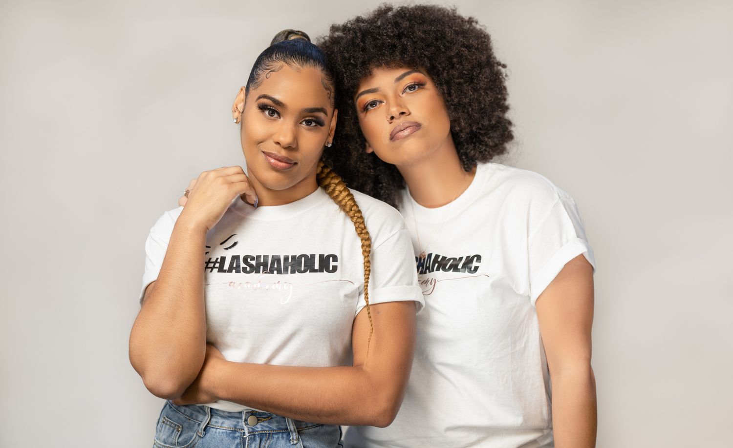 Two women in casual t-shirts pose against white background.