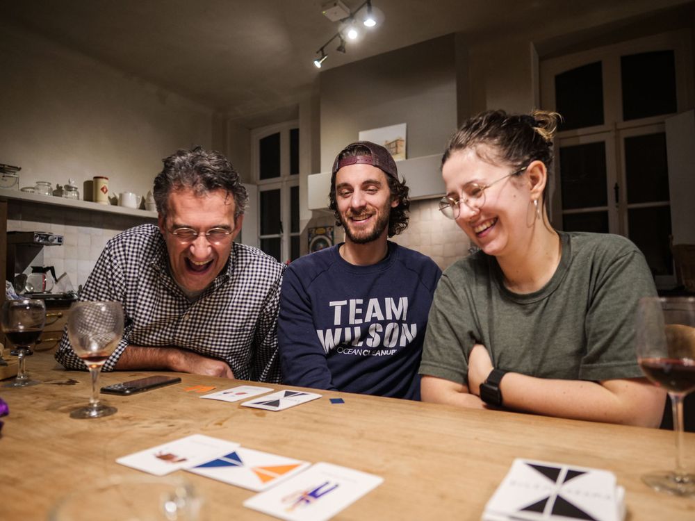 Colleagues all laugh and smile at cards during game.
