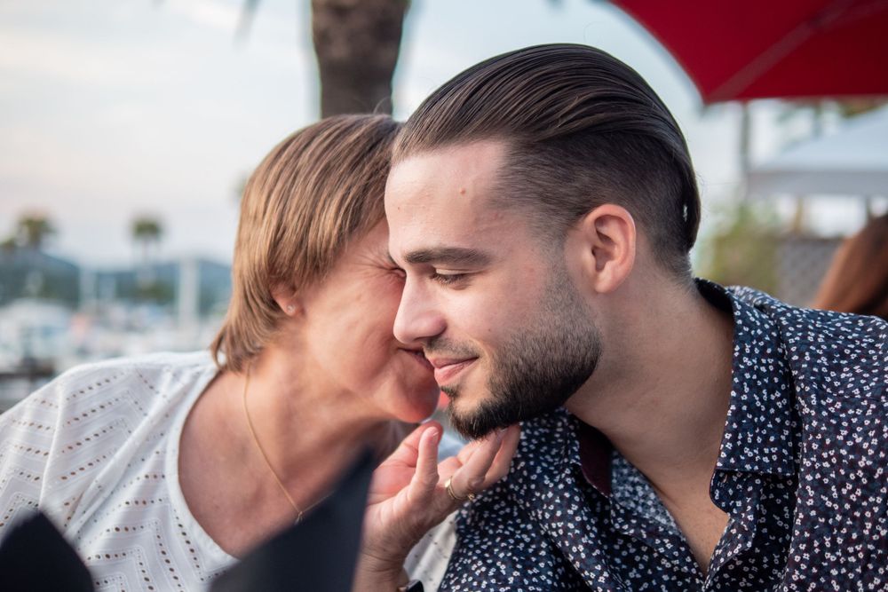Mother kisses son on cheek on the south coast of France.