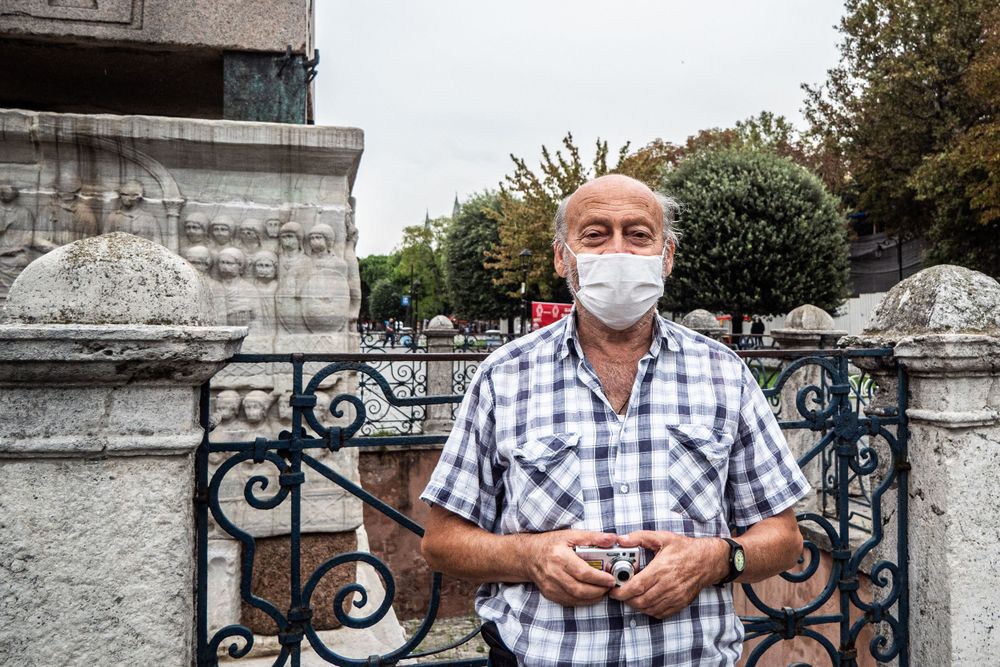 Proud local in Istanbul poses while holding camera and wearing mask.