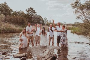 Group celebrating in shallow water during outdoor photo session.