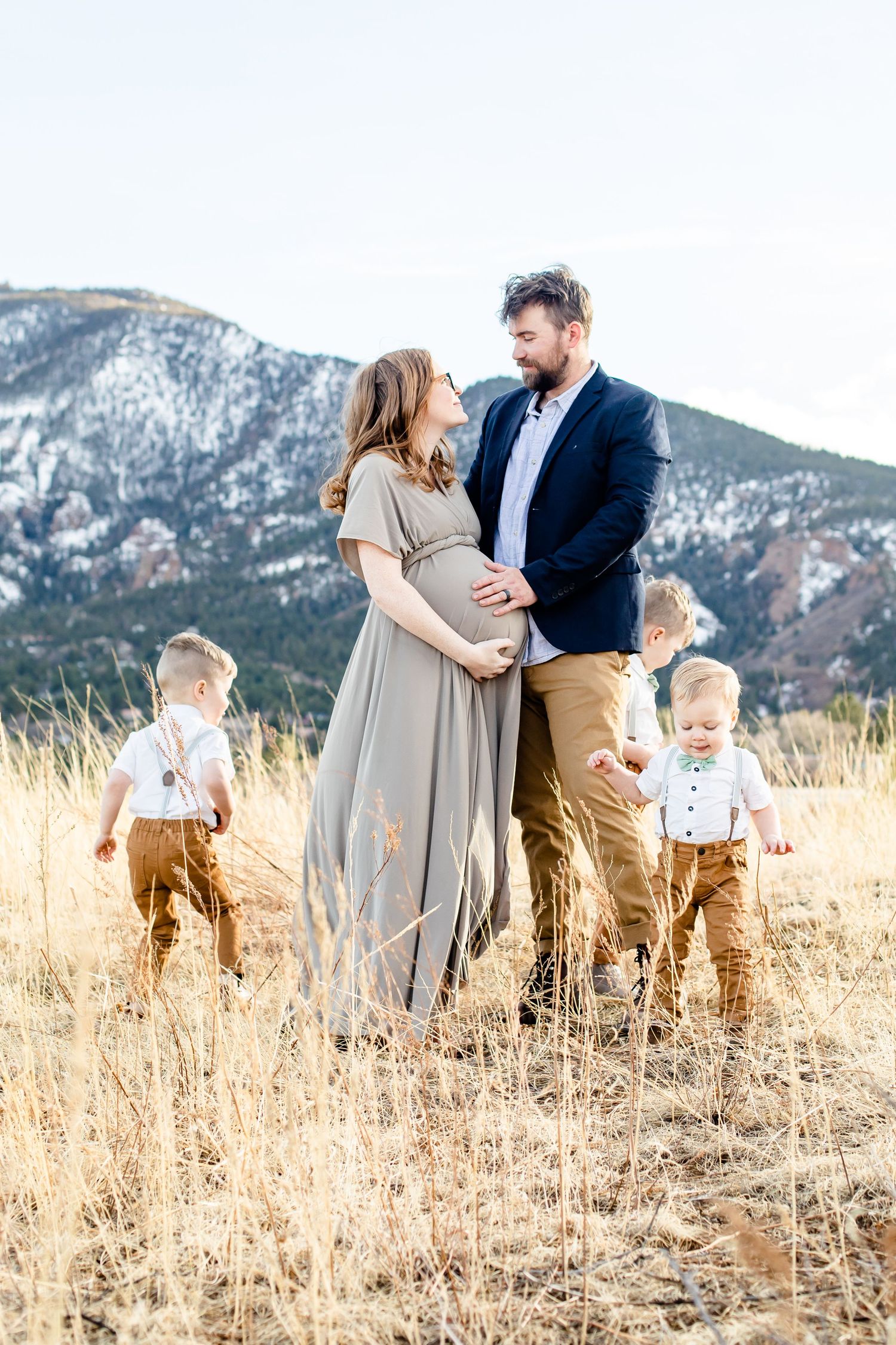 Expectant parents smile at each other while their three young boys play around them in Colorado Springs, Colorado.