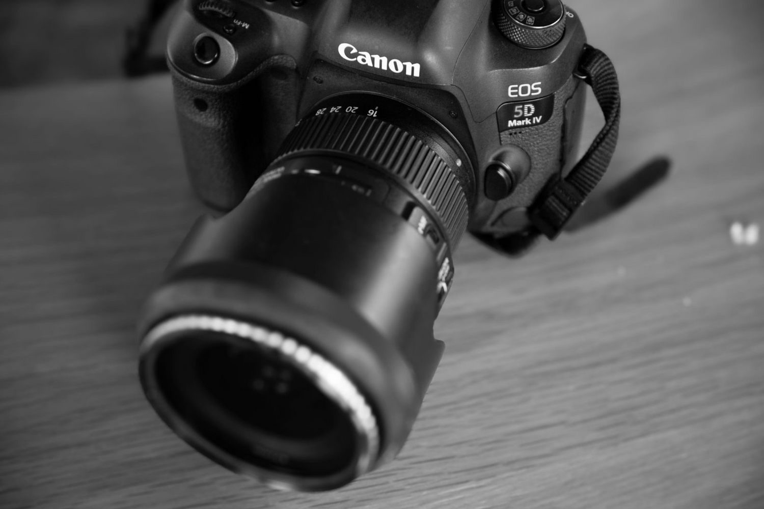 Close-up of Canon DSLR camera with zoom lens on wooden surface.