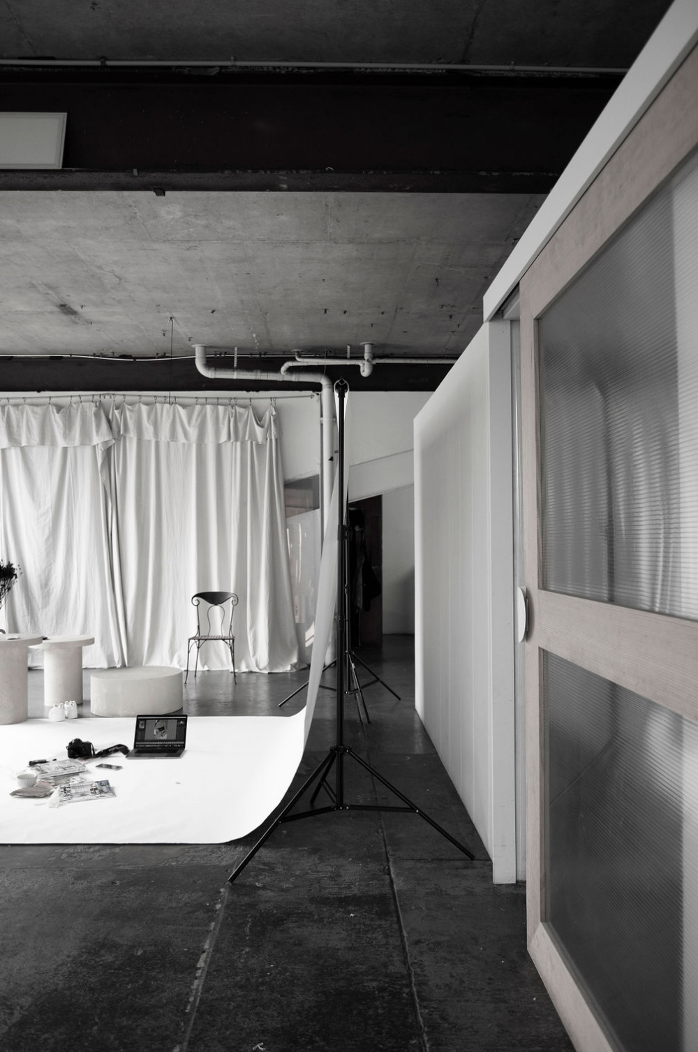 Black and white photo of photography studio setup with white backdrop and lighting equipment.