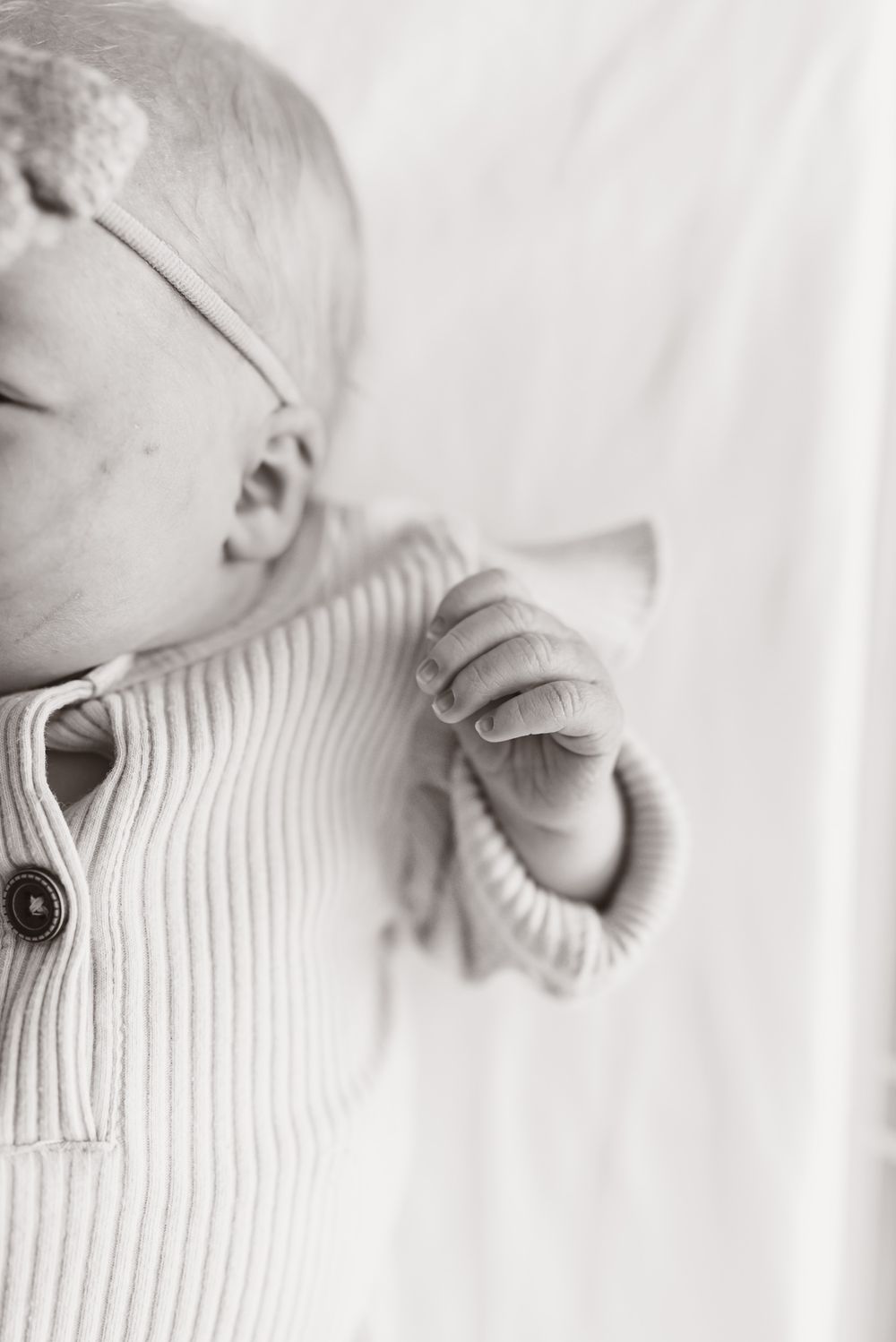 Black and white portrait of infant in ribbed sweater against white background.