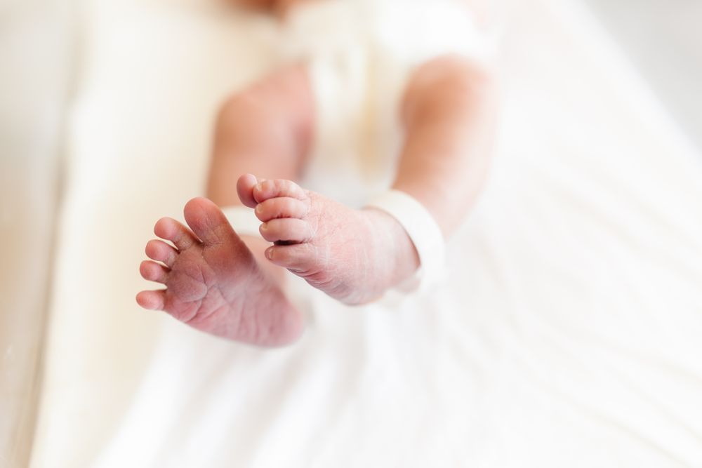 Delicate baby feet and toes against soft white background.