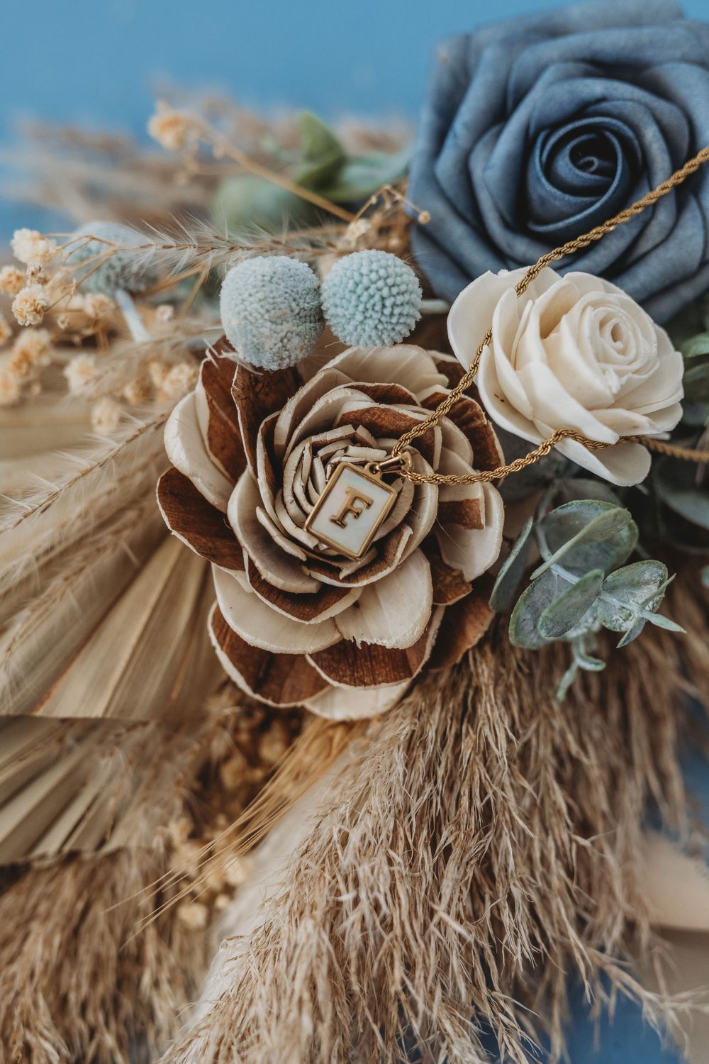 Artistically arranged dried pampas grass with gray and beige roses and silver berries in a boho-style floral arrangement.