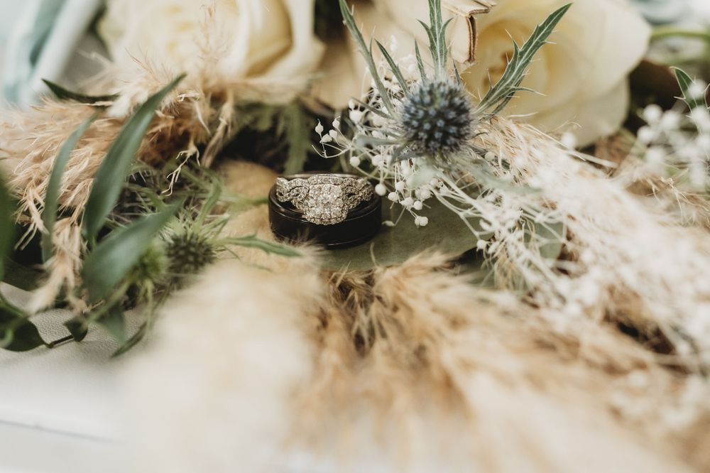 Closeup of a delicate floral arrangement with white roses, pampas grass and silvery foliage.