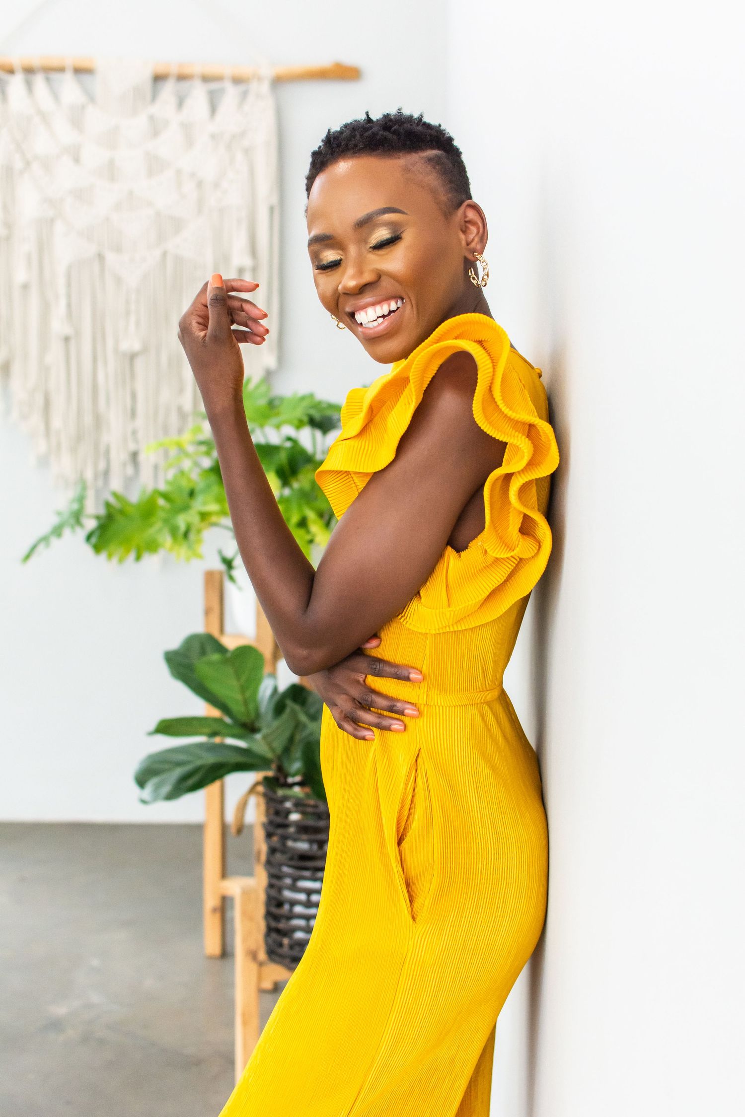 A vibrant yellow ruffled dress brings joy and elegance to a bright interior setting with tropical plants.