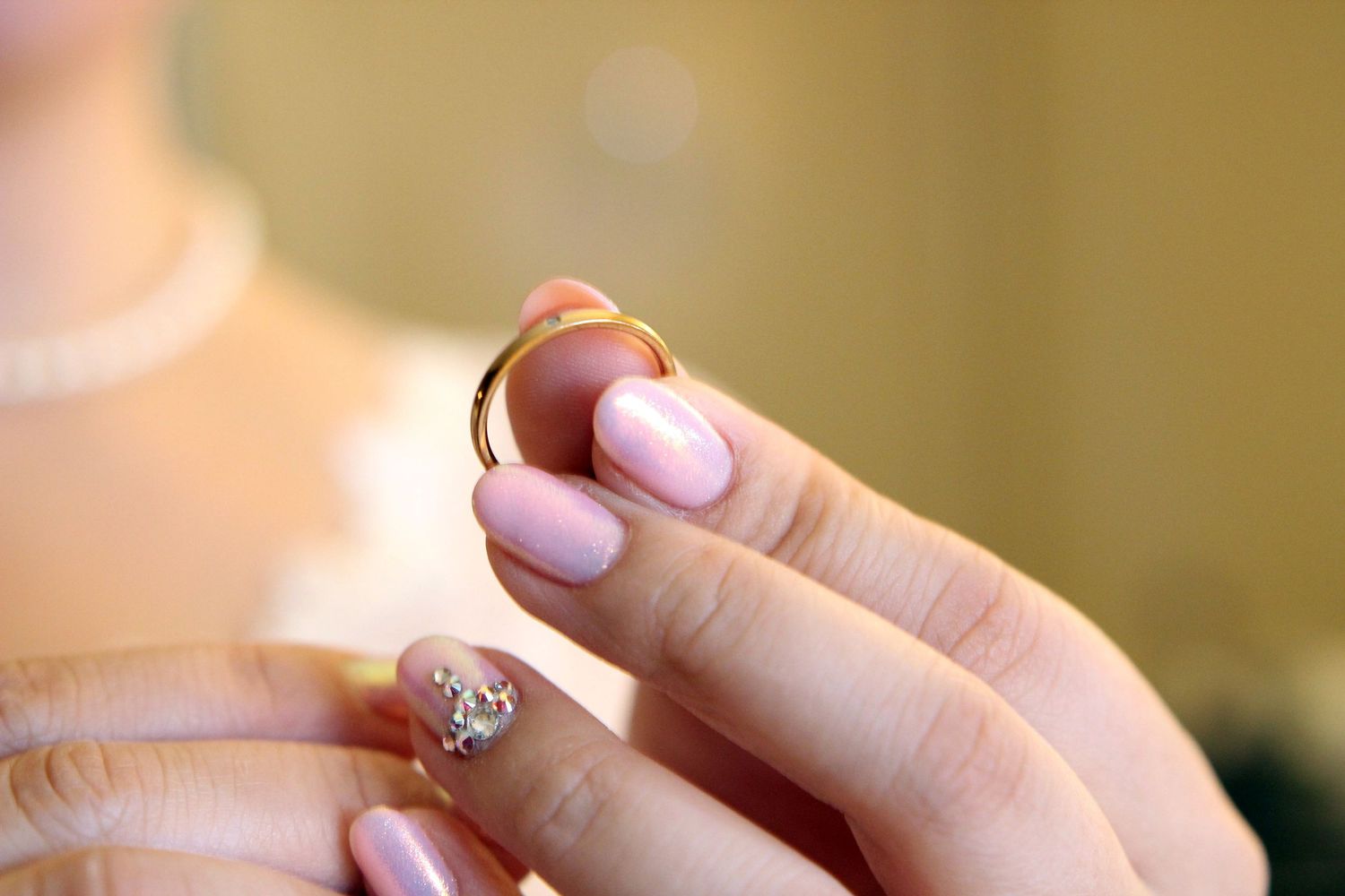 Close up of pink manicured nails with delicate crystal nail art decoration.