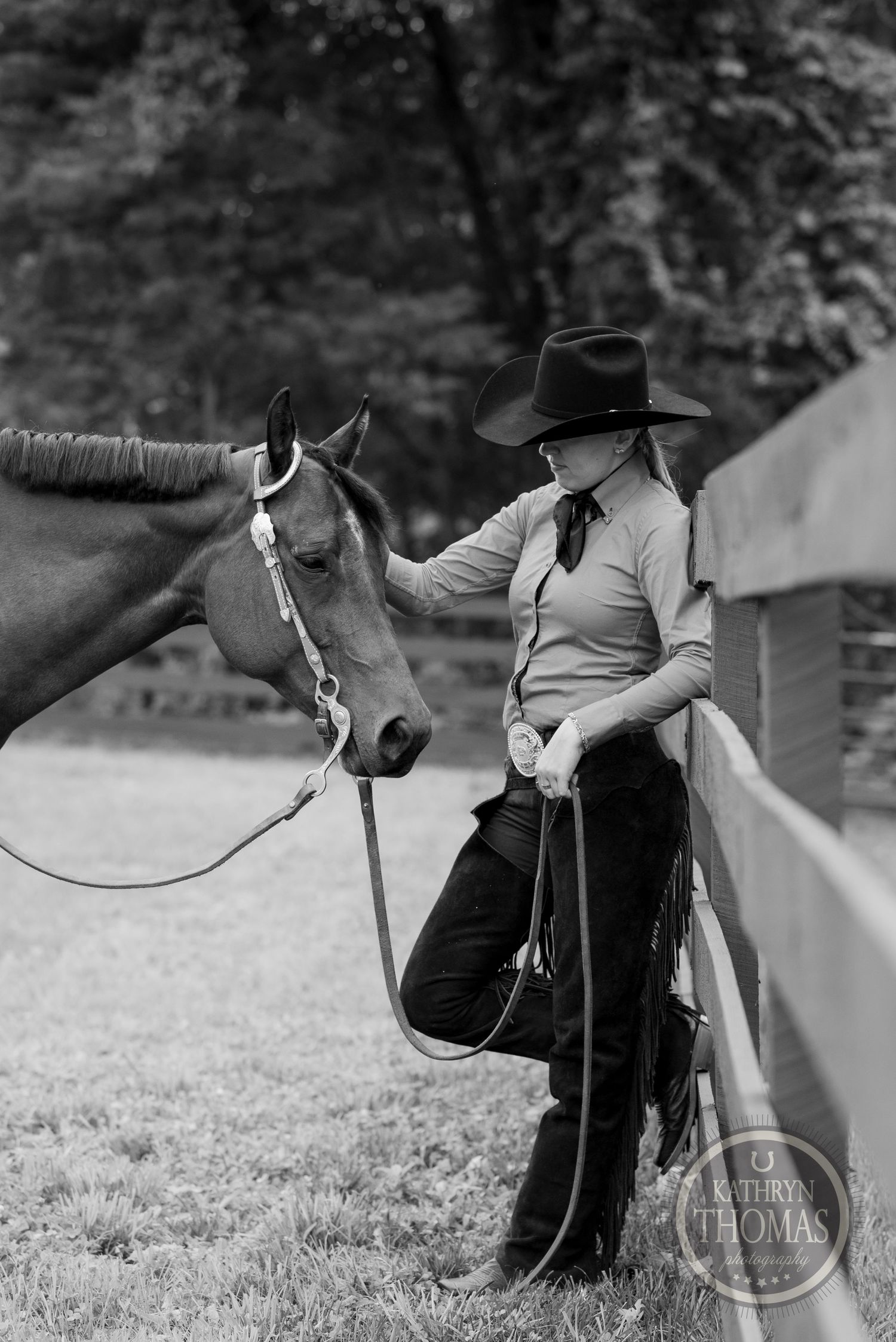 Black and white portrait of equestrian with horse in countryside setting.