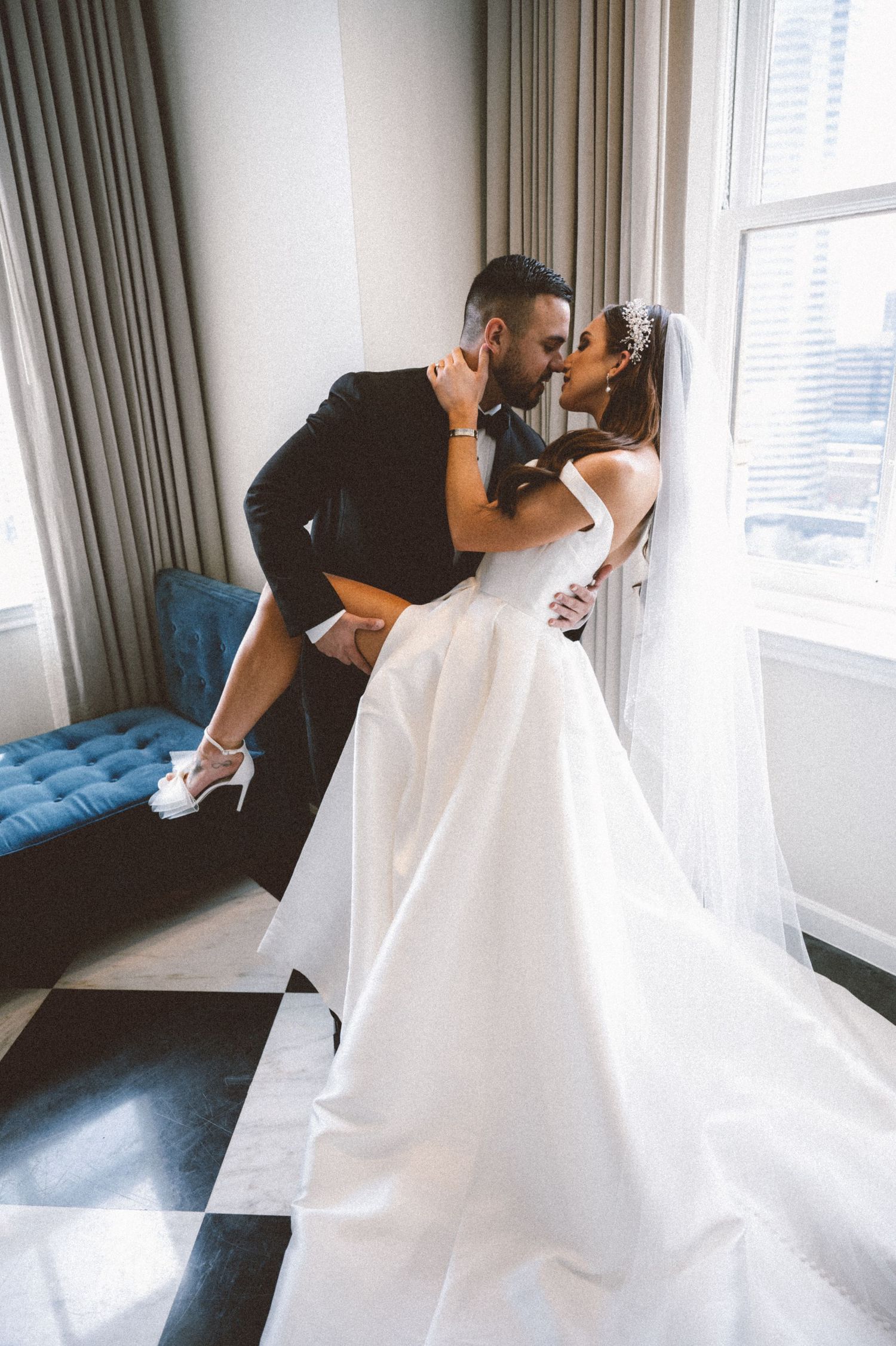 A romantic wedding moment captured by large windows in an elegant room.