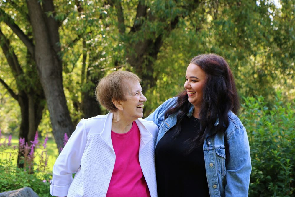 Two people share warm smiles while posing together in a park setting.