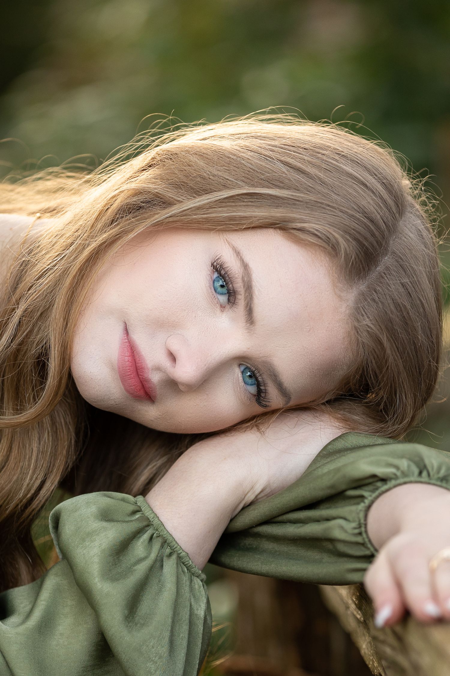 Portrait in soft natural light with green clothing and gentle bokeh background.