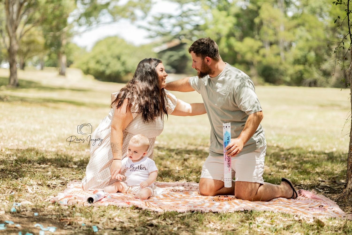 Young family enjoying a sunny outdoor picnic on a colorful blanket in a park.