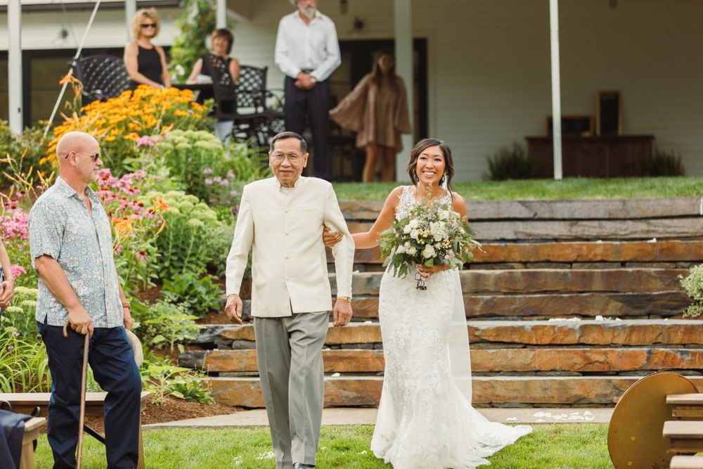 Wedding ceremony taking place on a porch decorated with colorful summer flowers.