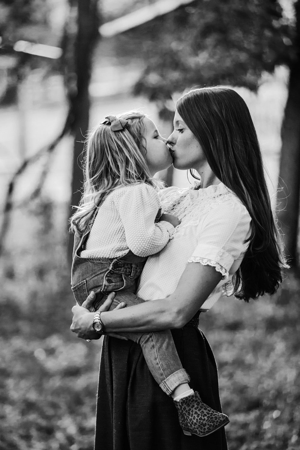 Black and white tender moment between parent and child in a forest setting.