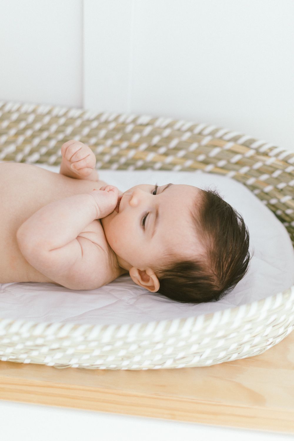 Peaceful nursery scene with woven changing basket on wooden surface.