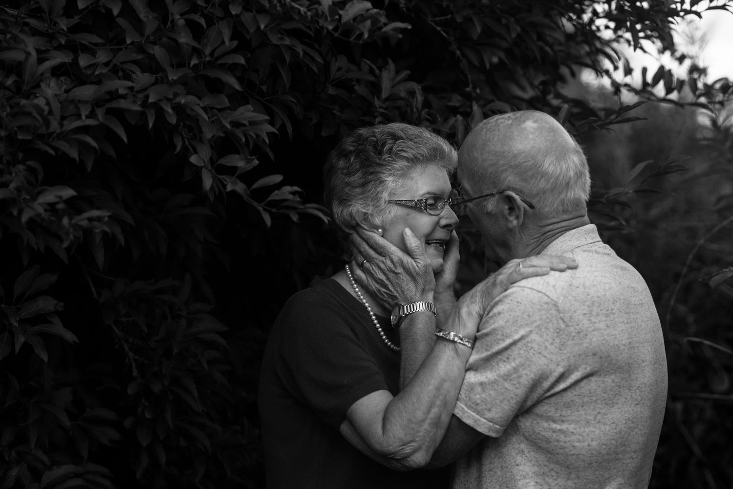 Black and white portrait of a couple sharing an affectionate moment outdoors.
