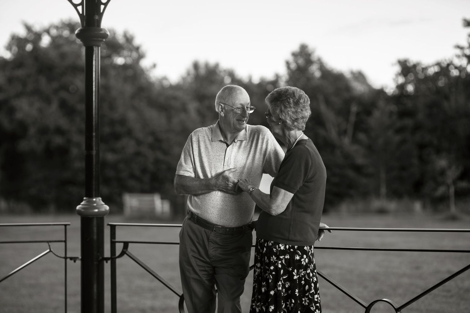 Elderly couple sharing a tender embrace in a park setting.