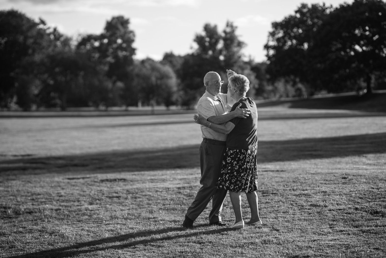 Black and white landscape photo with couple walking in parkland.