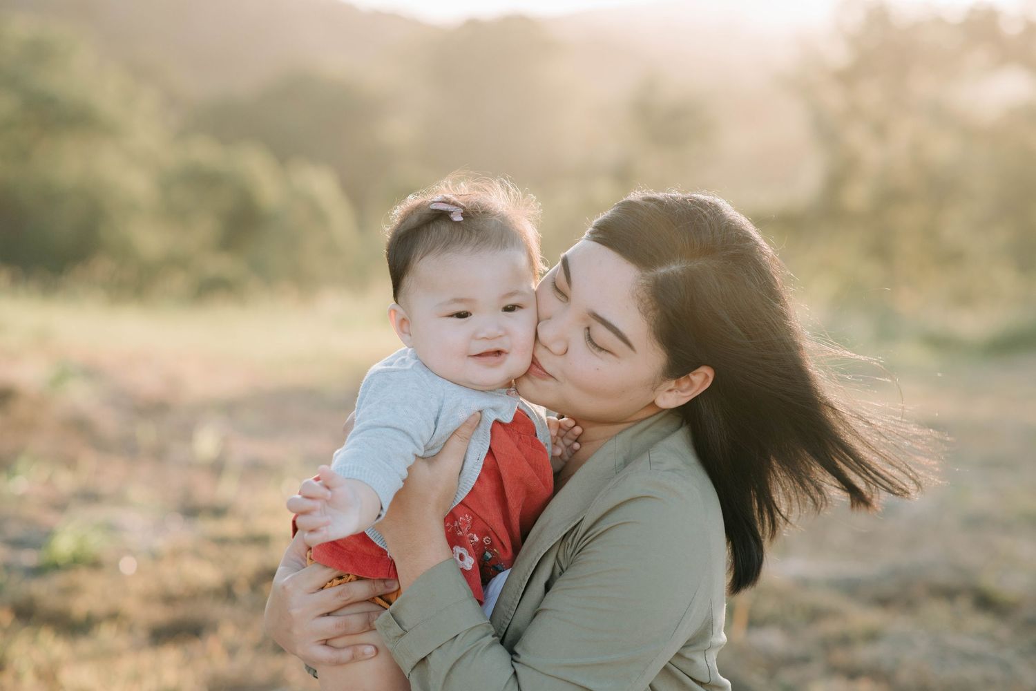 Mother and baby sharing joyful moment in golden sunset light.