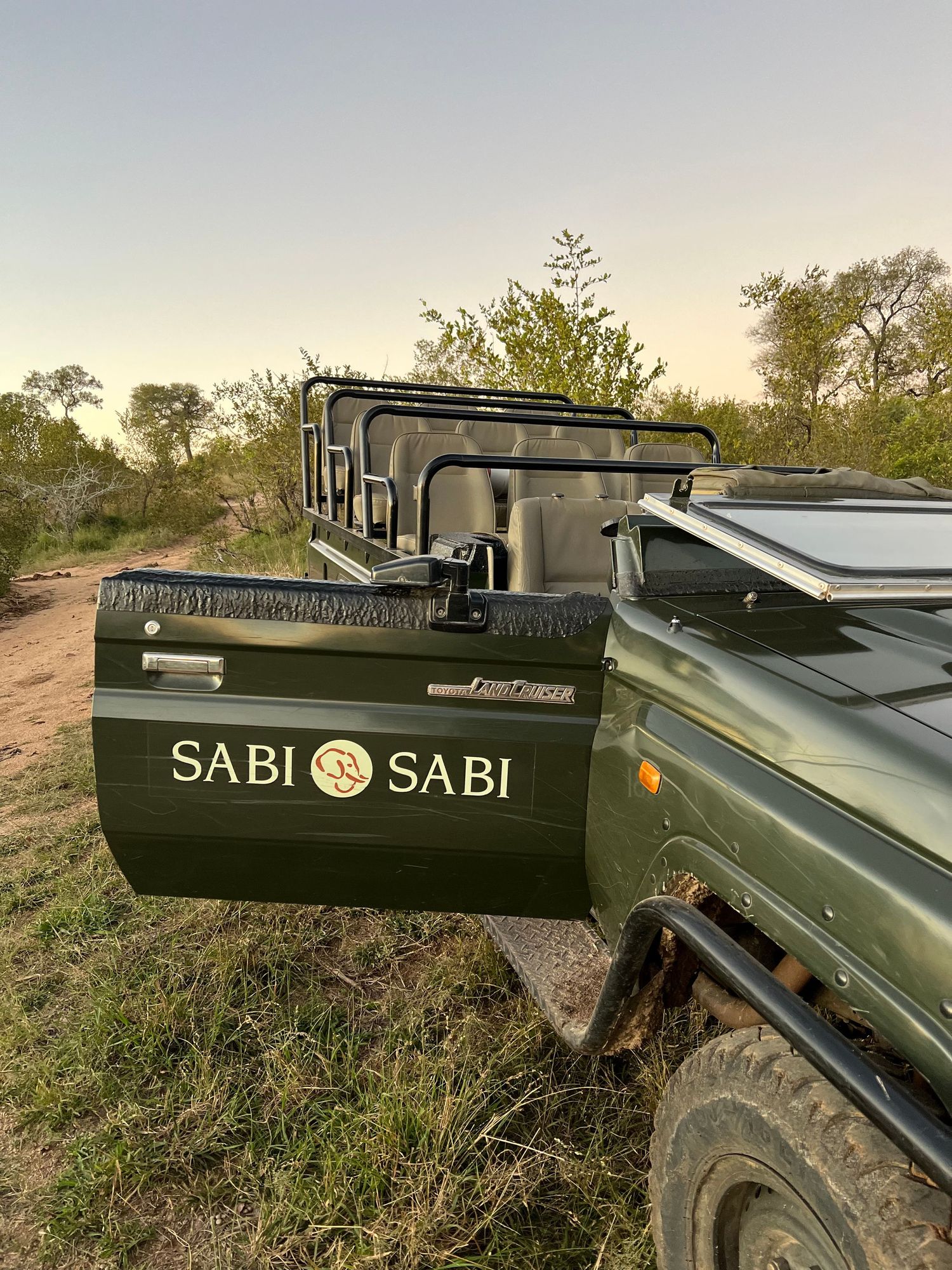 Safari vehicle with Sabi Sabi branding parked in natural bushveld terrain.
