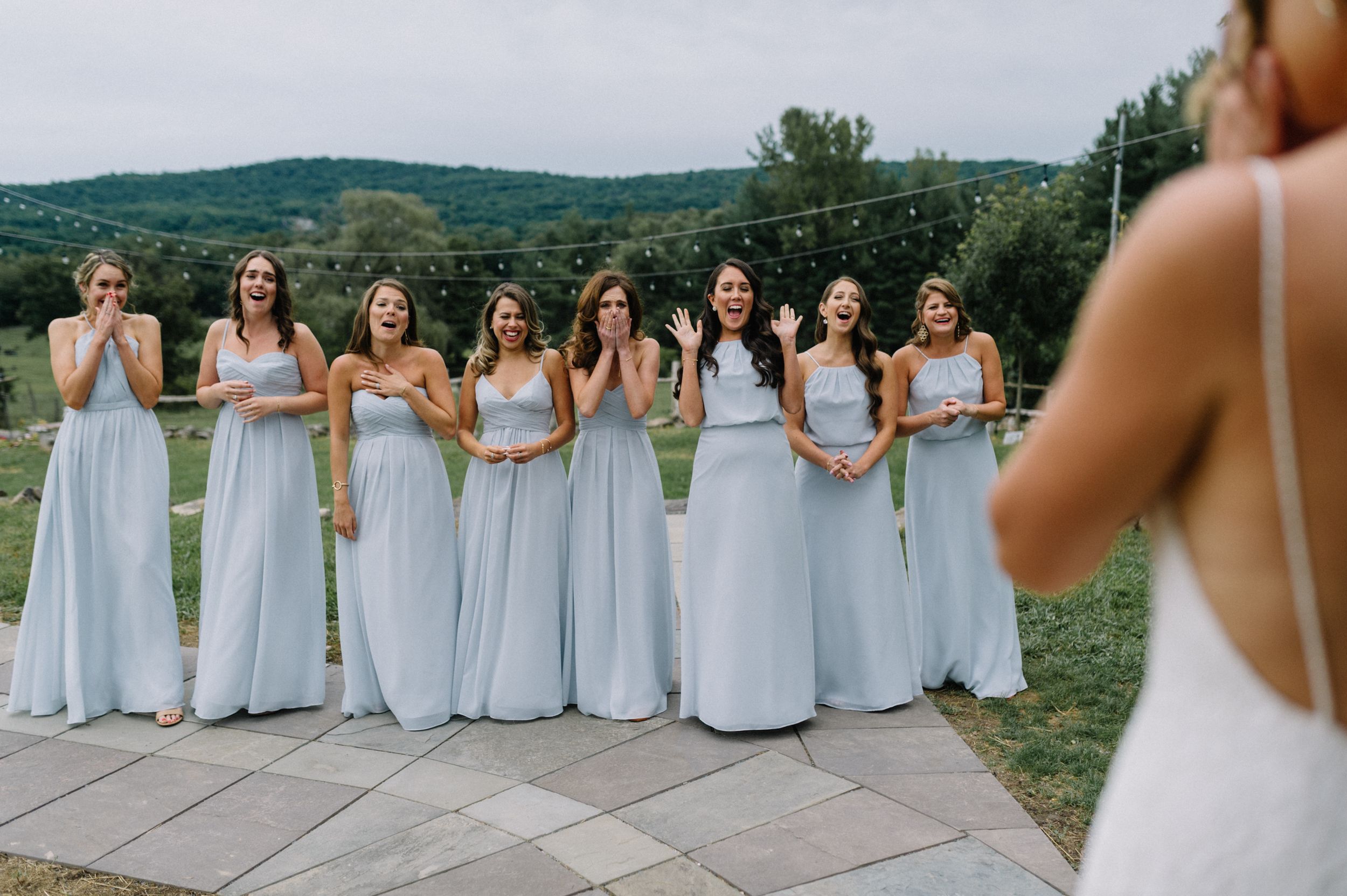 Bridesmaids surprised faces during first look with bride - capturing candid joy and excitement on a wedding day