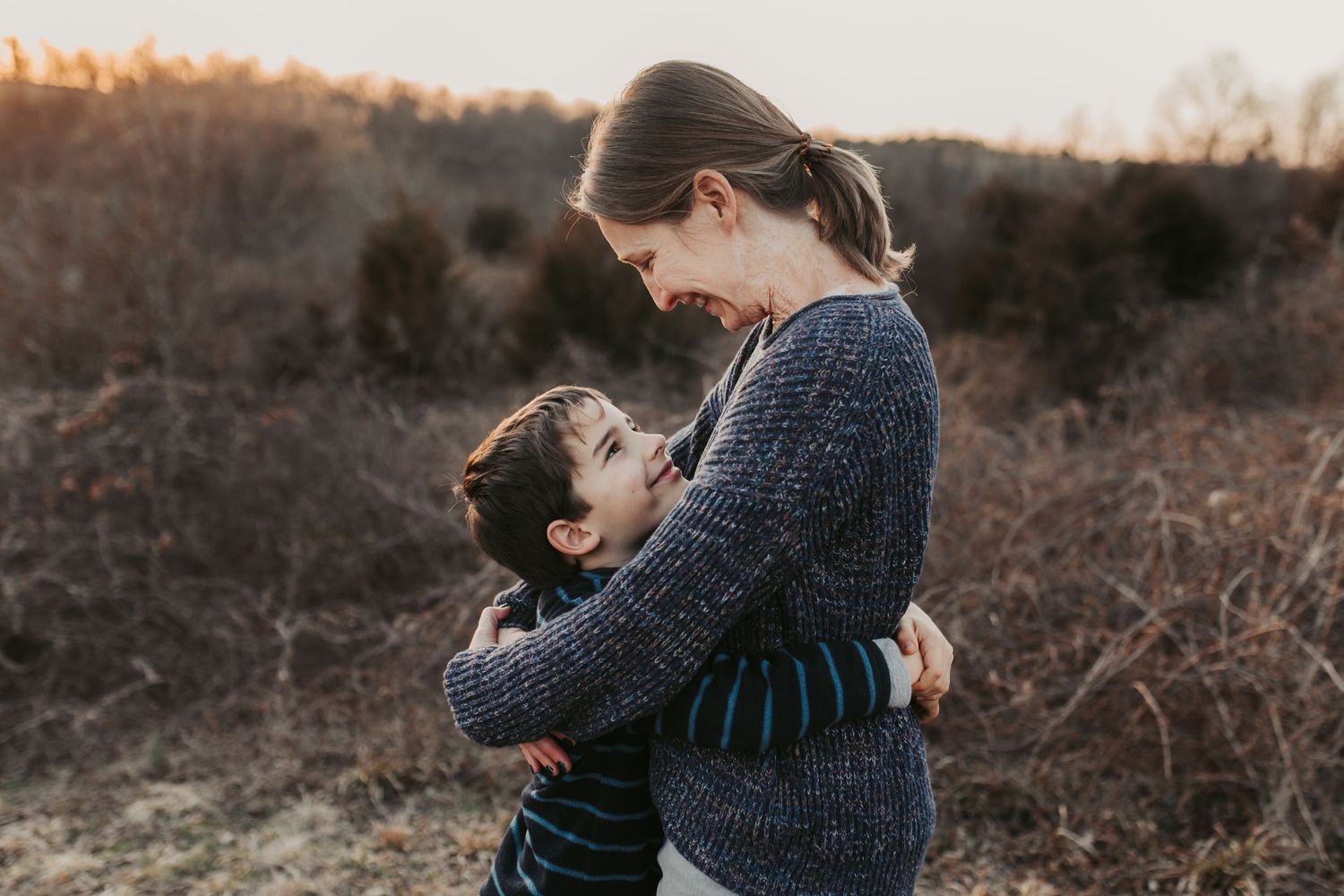 An intimate moment between two people in knit sweaters outdoors.