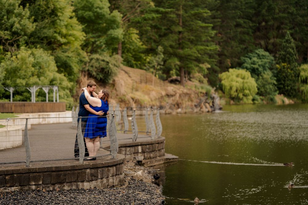 newly engaged plus size couple dressed in blue embracing in park cranbourne